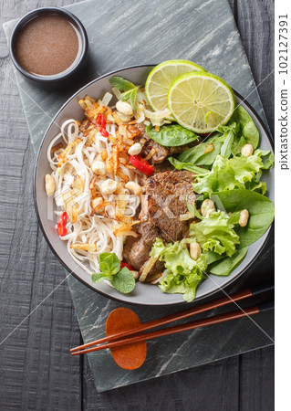 Vietnamese Beef Noodle Salad Pho Tron closeup on the plate. Vertical top view Vietnamese Beef Noodle Salad Pho Tron closeup on the plate. Vertical top view 102127391