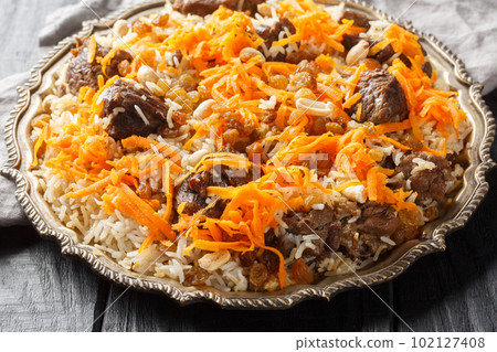 Afghan national dish Kabuli Pulao rice pilaf with lamb and raisin, carrot, nut, spices closeup on the plate. Horizontal Afghan national dish Kabuli Pulao rice pilaf with lamb and raisin, carrot, nut, spices closeup on the plate. Horizontal 102127408