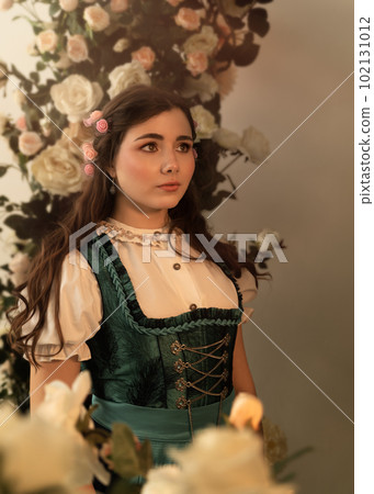 A young peasant woman standing in a garden with flowers dressed in a 19th century bavarian dress. 102131012