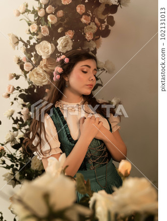 A young peasant woman standing in a garden with flowers dressed in a 19th century bavarian dress. A young peasant woman standing in a garden with flowers dressed in a 19th century bavarian dress. 102131013