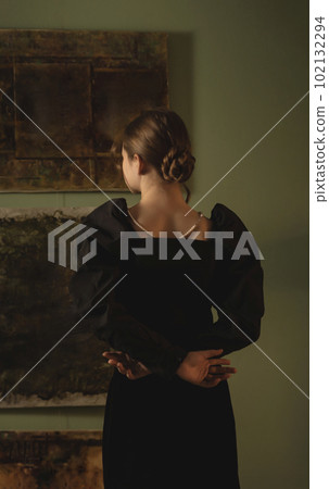 A young girl standing in an art studio looking at the pictures and dreaming. A young girl standing in an art studio looking at the pictures and dreaming. 102132294