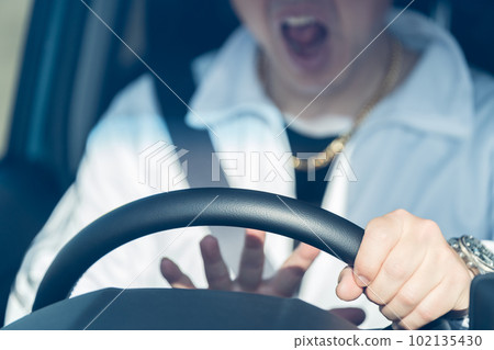 The hand of a middle-aged male driver who holds the steering wheel while shouting and sounds the horn The hand of a middle-aged male driver who holds the steering wheel while shouting and sounds the horn 102135430