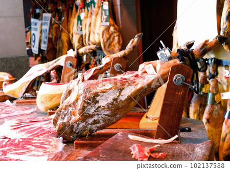 Legs of traditional Spanish jamon fixed on wooden jamoneras ready for sale Legs of traditional Spanish jamon fixed on wooden jamoneras ready for sale 102137588