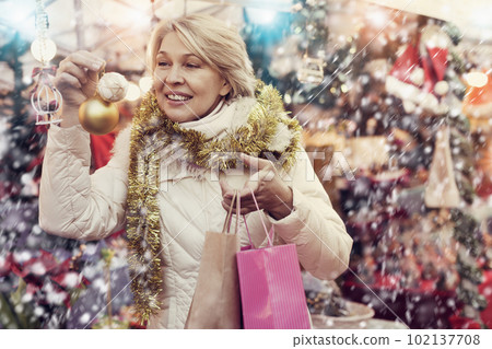 Positive mature female buying decoration at Christmas Fair Positive mature female buying decoration at Christmas Fair 102137708
