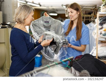 Worker giving woman her clean clothes 102138247