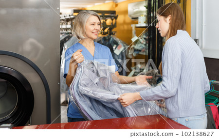Nice worker giving woman her clean clothes 102138627
