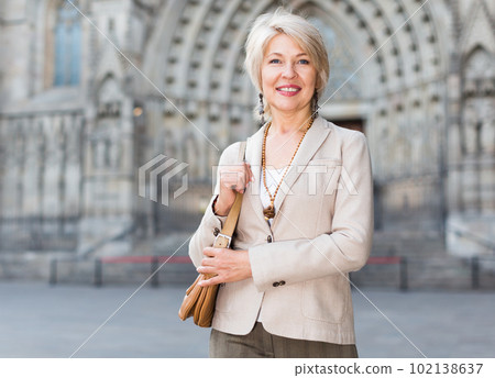 Cheerful mature female is walking in classic jacket 102138637