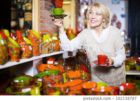 Smiling mature female holding ceramic cups Smiling mature female holding ceramic cups 102138787