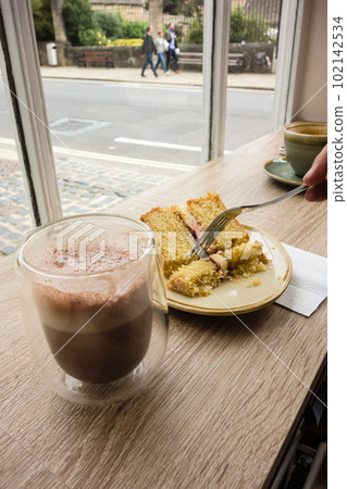 Coffee and cake placed on the table by the window of the cafe The streets of Oxford, England 102142534