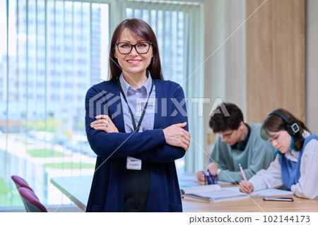 Portrait of middle aged female teacher, looking at camera, in college classroom 102144173