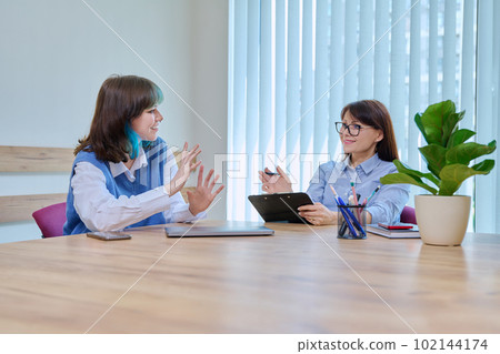 Woman social worker, mentor interviewing, talking to young teen female in office Woman social worker, mentor interviewing, talking to young teen female in office 102144174