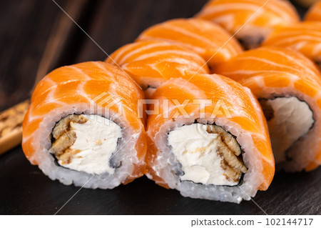 Close up Sushi roll philadelphia with salmon and eel and cream cheese on black background close-up. Sushi menu. Japanese food concept 102144717