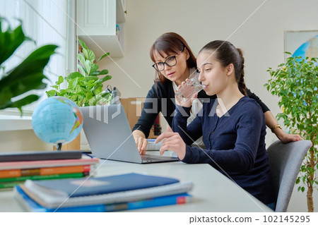 Teenage girl studying, female teacher with textbook helps tells teaches Teenage girl studying, female teacher with textbook helps tells teaches 102145295