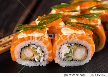 Sushi roll philadelphia with crab and cucumber and cream cheese, caviar on black background close-up. Sushi menu. Japanese food concept Sushi roll philadelphia with crab and cucumber and cream cheese, caviar on black background close-up. Sushi menu. Japanese food concept 102145487
