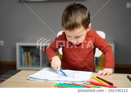 A cute little toddler boy of two years old draws with markers in the album in the children's room at home. Educational activities for kids A cute little toddler boy of two years old draws with markers in the album in the children's room at home. Educational activities for kids 102146122