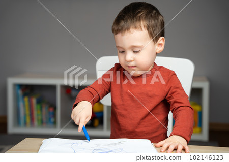 A cute attentive little toddler boy of two years old draws with markers in the album in the children's room at home. Educational activities for kids A cute attentive little toddler boy of two years old draws with markers in the album in the children's room at home. Educational activities for kids 102146123