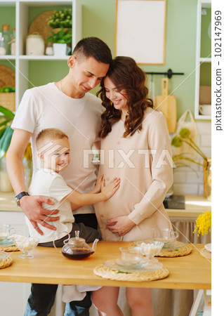 a loving family. pregnant mom, son and dad In the kitchen. a cozy house  102147969