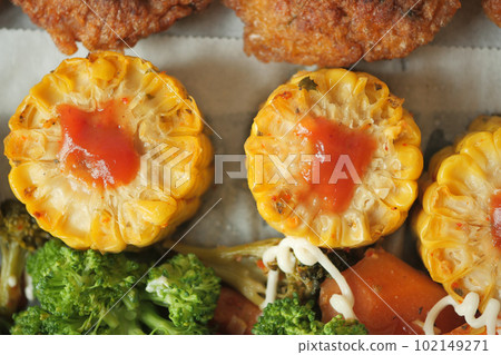 Ears of corn baked with herbs on white baking paper 102149271