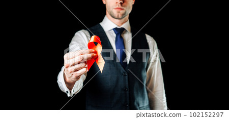 Hiv aids. Red ribbon in hiv world day isolated on dark background. Man holding awareness aids and cancer symbol. Health, Medical sign. copy space. Hiv aids. Red ribbon in hiv world day isolated on dark background. Man holding awareness aids and cancer symbol. Health, Medical sign. copy space. 102152297
