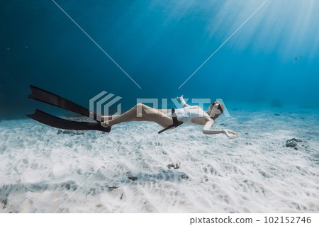 Freediver girl in white swimwear glides in tropical blue ocean 102152746