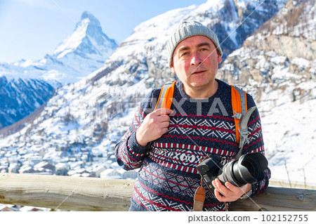 Smiling man with camera hiking in Swiss Alps in wintertime Smiling man with camera hiking in Swiss Alps in wintertime 102152755