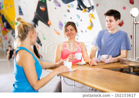 Young man and two women having conversation at bar counter in climbing center 102153617