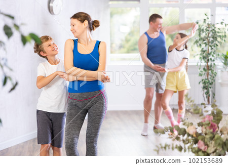 Happy mother and son practicing dance in pairs together with other family members 102153689