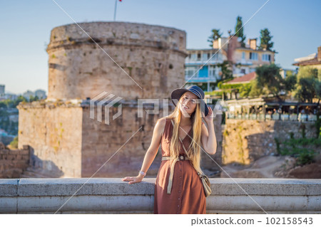 Woman tourist on background of Hidirlik Tower in Antalya against the backdrop of the Mediterranean bay of the ancient Kaleici district, Turkey. Turkiye Woman tourist on background of Hidirlik Tower in Antalya against the backdrop of the Mediterranean bay of the ancient Kaleici district, Turkey. Turkiye 102158543