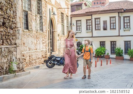 Mom and son tourists in Old town Kaleici in Antalya. Turkiye. Panoramic view of Antalya Old Town port, Taurus mountains and Mediterrranean Sea, Turkey. Traveling with kids concept 102158552