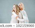 Portrait of young blonde women friends in sportswear on background of grey wall 102159060