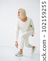 Full length portrait of smiling young blonde woman in sportswear on background of white wall 102159255