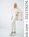 Full length portrait of smiling young blonde woman in sportswear on background of white wall 102159256
