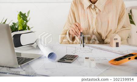 Architect interior design drawing with divider compass on house plan blueprint paper for editing on table desk at architecture office, Engineer sketching construction, Architectural project workplace Architect interior design drawing with divider compass on house plan blueprint paper for editing on table desk at architecture office, Engineer sketching construction, Architectural project workplace 102159954