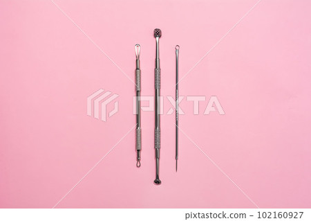 Steel tools for facial cleansing on pink background. Uno spoon. 102160927