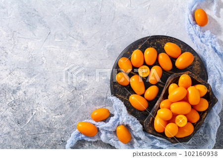 Fresh ripe kumquat on an old wooden board. Ripe fruit top view Fresh ripe kumquat on an old wooden board. Ripe fruit top view 102160938