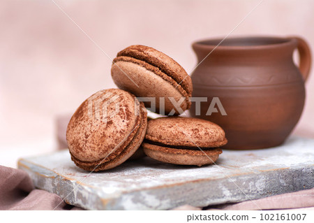 A cup of coffee and chocolate macarons on a wooden board. Breakfast concept. A cup of coffee and chocolate macarons on a wooden board. Breakfast concept. 102161007