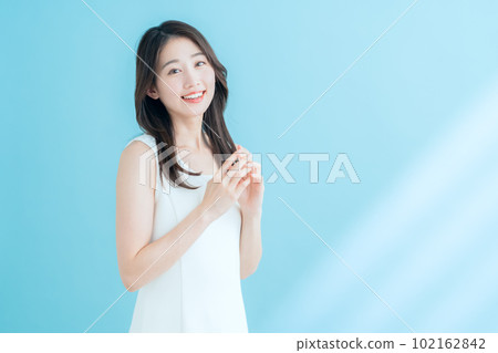 A young woman doing skin care on a blue background where the sun shines 102162842