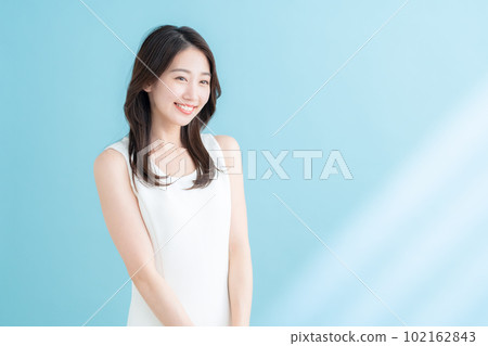 A young woman doing skin care on a blue background where the sun shines A young woman doing skin care on a blue background where the sun shines 102162843