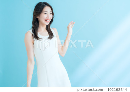 A young woman doing skin care on a blue background where the sun shines 102162844