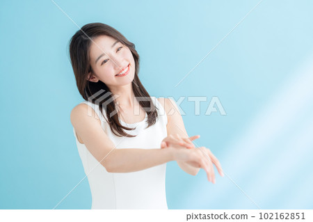 A young woman doing skin care on a blue background where the sun shines 102162851