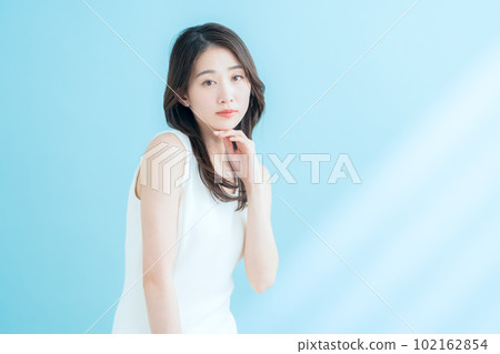 A young woman doing skin care on a blue background where the sun shines 102162854