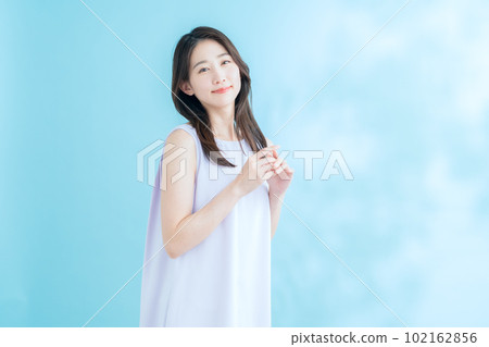 A young woman doing skin care on a blue background where the sun shines 102162856