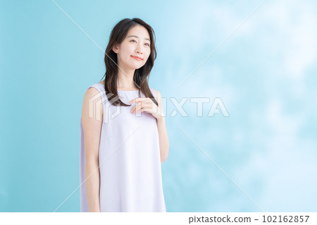 A young woman doing skin care on a blue background where the sun shines 102162857