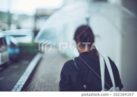 Back view of a woman holding an umbrella 102164167