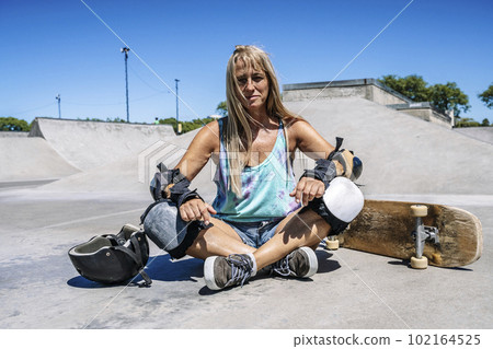 Smiling middle age woman portrait with skateboard in sport lifestyle at summer sunny day. Street urban sporty lifestyle concept. 102164525