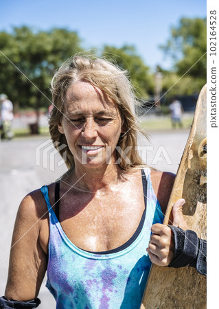 Smiling middle age woman portrait with skateboard in sport lifestyle at summer sunny day. Street urban sporty lifestyle concept. Smiling middle age woman portrait with skateboard in sport lifestyle at summer sunny day. Street urban sporty lifestyle concept. 102164528