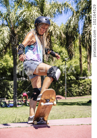 Smiling middle age woman portrait with skateboard in sport lifestyle at summer sunny day. Street urban sporty lifestyle concept. Smiling middle age woman portrait with skateboard in sport lifestyle at summer sunny day. Street urban sporty lifestyle concept. 102164529