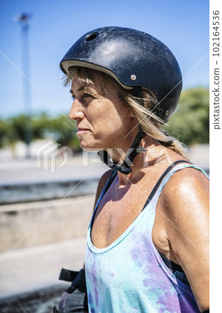 Smiling middle age woman portrait with skateboard in sport lifestyle at summer sunny day. Street urban sporty lifestyle concept. Smiling middle age woman portrait with skateboard in sport lifestyle at summer sunny day. Street urban sporty lifestyle concept. 102164536