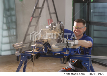 Happy foreman in goggles smiles sawing wood with equipment 102164922