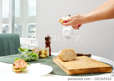 Hands of unrecognizable woman spreading ricotta on sandwich 102165910